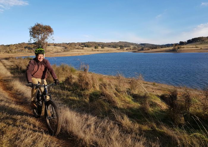Man riding his mountain bike on a grassy trail along a dam, Oberon - Credit: Oberon Visitor Information Centre