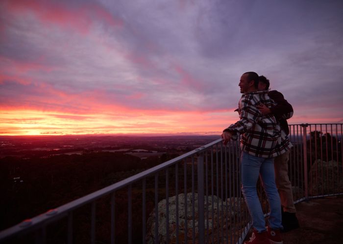 Couple enjoying a spectacular sunset over the valley from Pinnacle Lookout, Canobolas