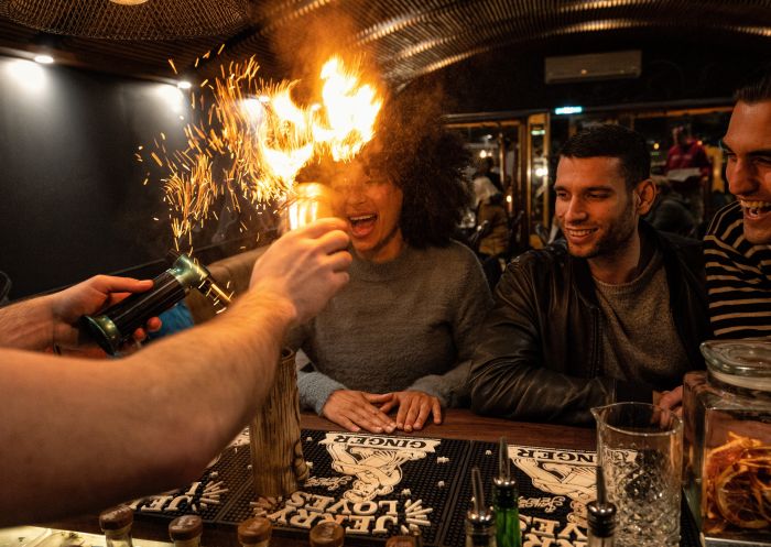 Friends enjoying a Bartendar creating their cocktails with fire at The Bootlegger Bar, Katoomba