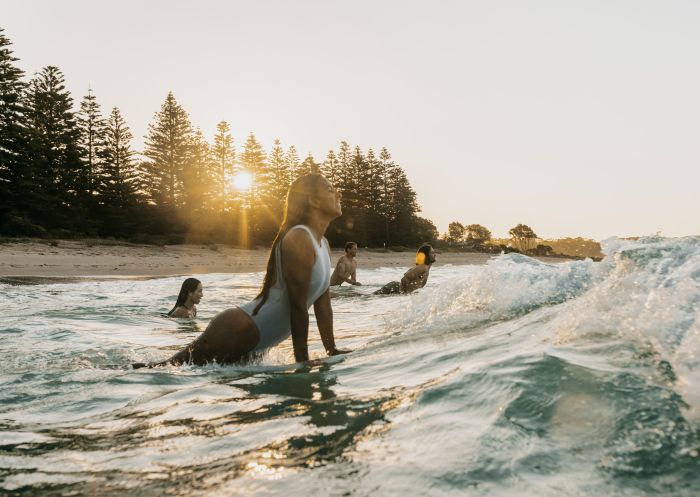 A young woman surfing in the afternoon at Murramarang Beachfront Holiday Resort, South Durras