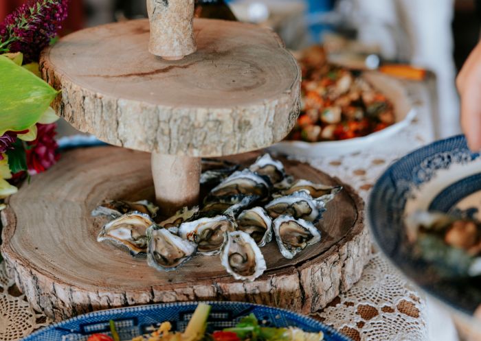 A tiered serving tray of oysters and some plates of starters on a VIP Private Tours, Narooma