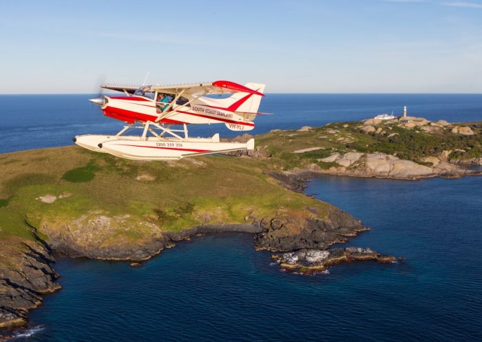 A red and white seaplane flying over Montague Island on a South Coast Seaplanes tour- Credit: Toby Whitelaw