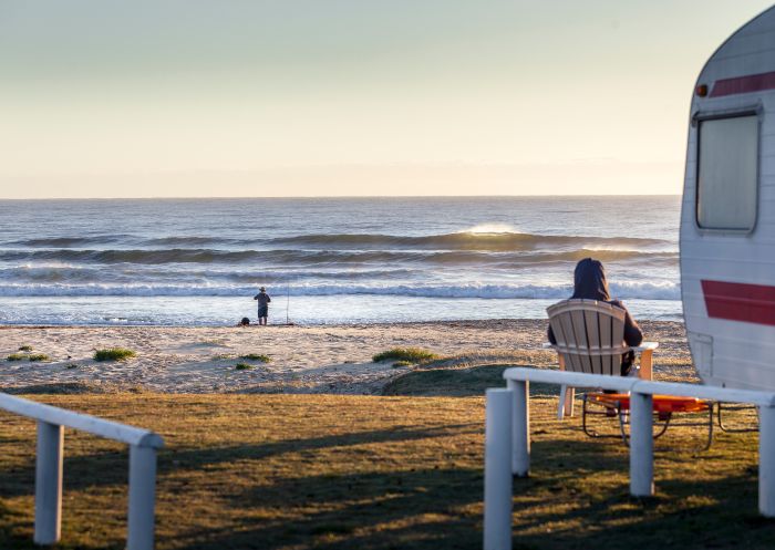 Caravan parked next to a beach while campers enjoy beach fishing and relaxing in a camp chair at Potato Point - Credit: Eurobodalla Coast Tourism