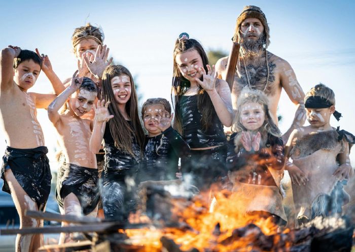 Children and a man in indigenous dress surrounding an open fire, Orange - Credit: Orange360