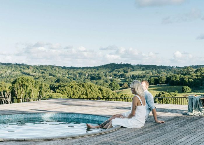 Couple sit on pool deck with their feet in the water, Heartwood Farm Byron Bay, Federal - Credit: Heartwood Farm Byron Bay
