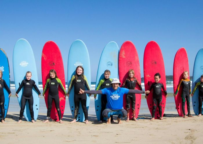 A class of surfing students on the beach standing in a line with their surf boards, Broulee