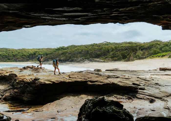 Zwei Personen gehen über Felsen vor dem Hintergrund des Emily Miller Beach - Bildnachweis: Department of Planning and Environment (NSW)