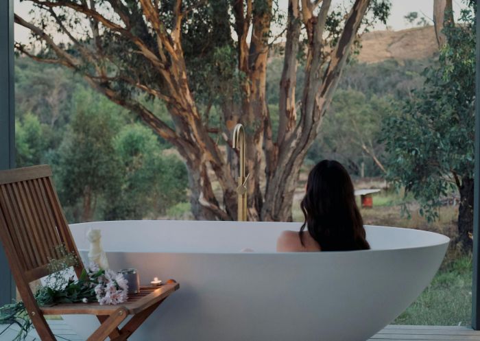 A woman in a white bath on a verandah overlooking a giant eucalyptus tree, Mount Adrah - Credit: Kestrel Nest EcoHut