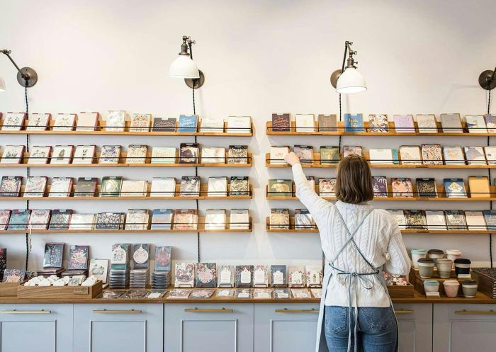 Woman arranging greeting cards on shelves in a stationery store interior at Bespoke Letterpress, Bowral - Credit: Bespoke Letterpress