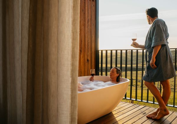 Couple enjoying bath and wine from balcony at Cupitt's Estate Villas, Ulladulla