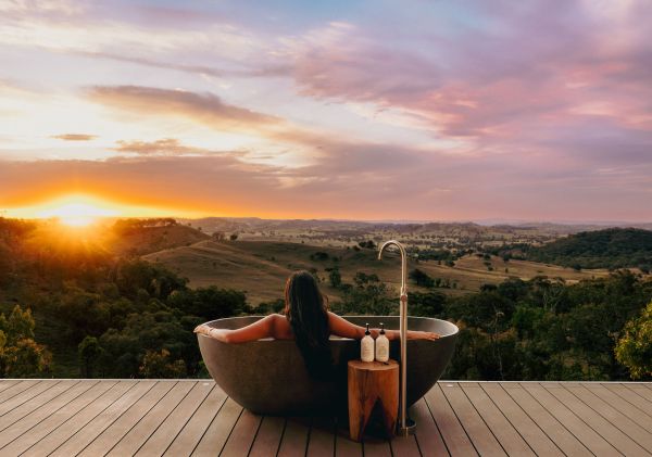 Frau genießt den Sonnenuntergang in einer Badewanne im Freien im Sierra Escape Luxury Glamping, Mudgee – Bildnachweis: Sierra Escape