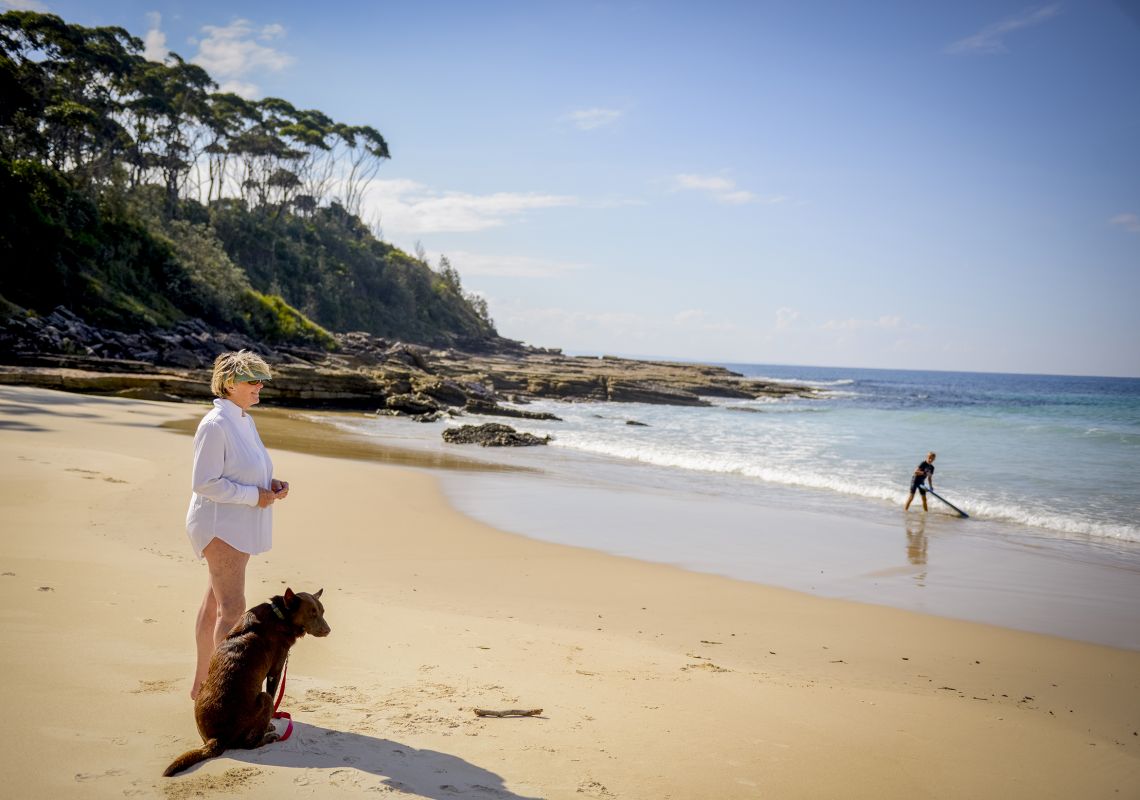 A woman and her dog on a beach, Bawley Point