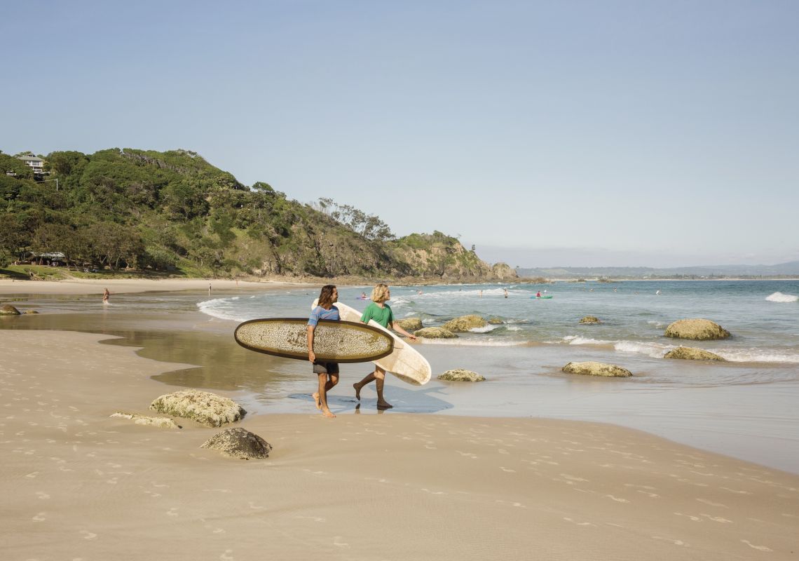 Two surfers holding their longboards survey Wategos Beach, Byron Bay