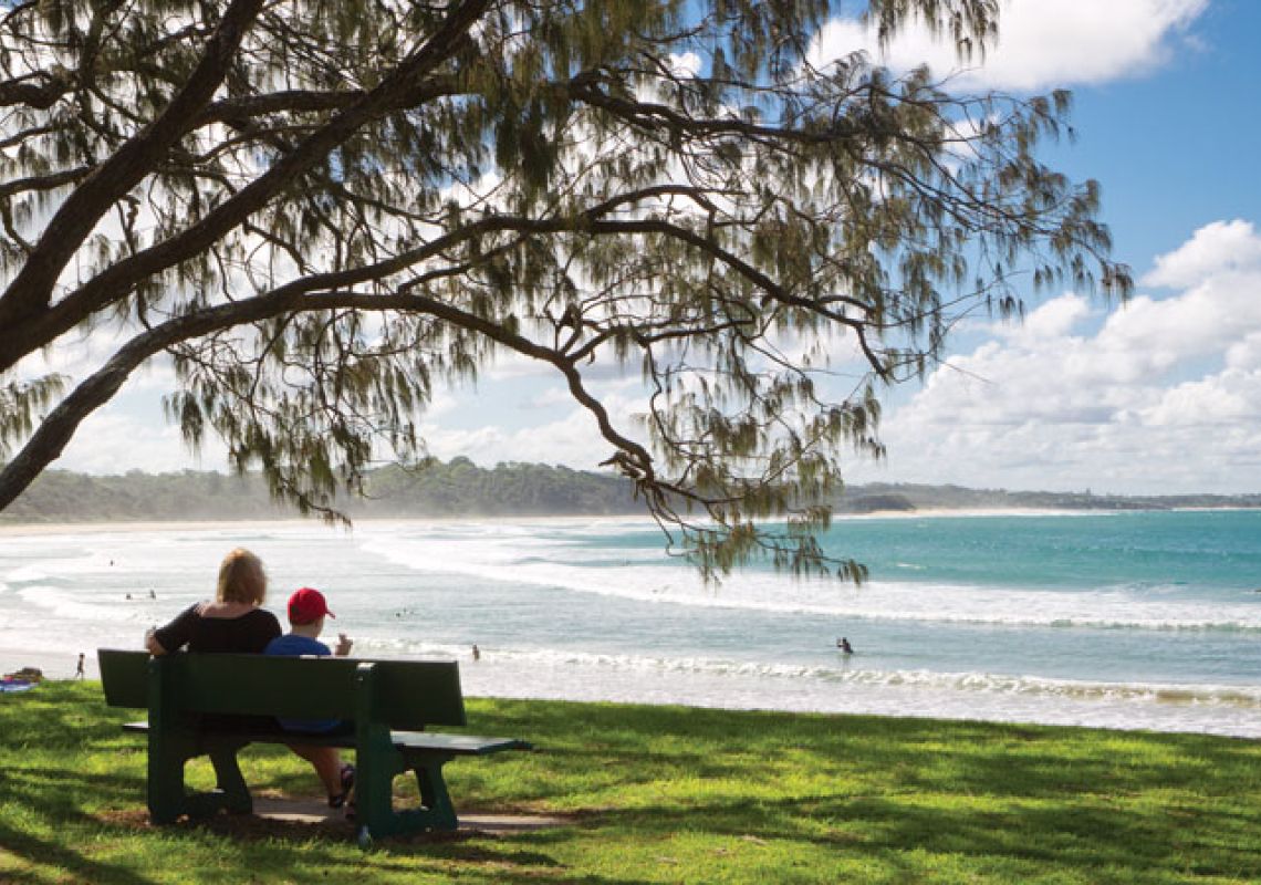 Mother and son sitting in picnic area by Woolgoolga Beach on the Coffs Coast.