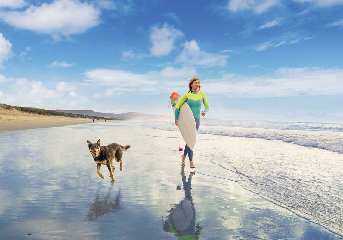 Woman and her pet dog out for a morning surf at Shoalhaven Heads, South Coast