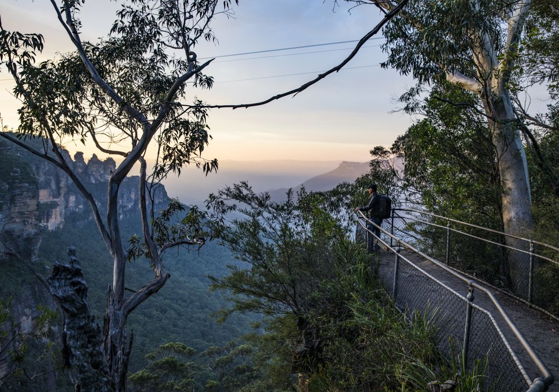 Man enjoying the sun rising over the Three Sisters from the Furber Steps-Scenic Railway walking track
