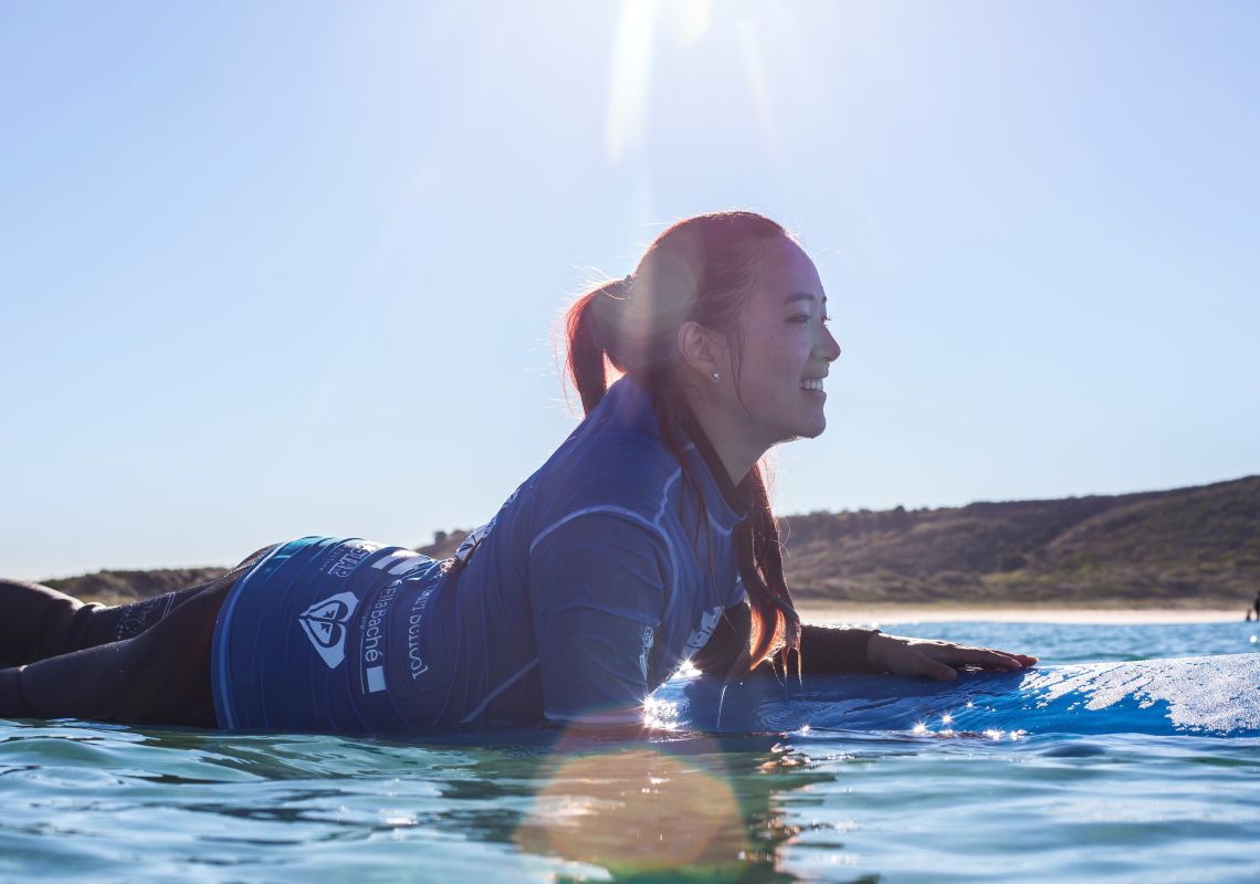 Woman learning to surf with Pines Surfing Academy Surf School at Killalea Beach ('The Farm'), Shell Cove, Shellharbour Area