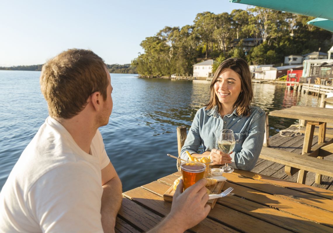 Couple enjoying fish and chips by the water at Tuross Boatshed & Cafe, Tuross Head, Batemans Bay Area, South Coast