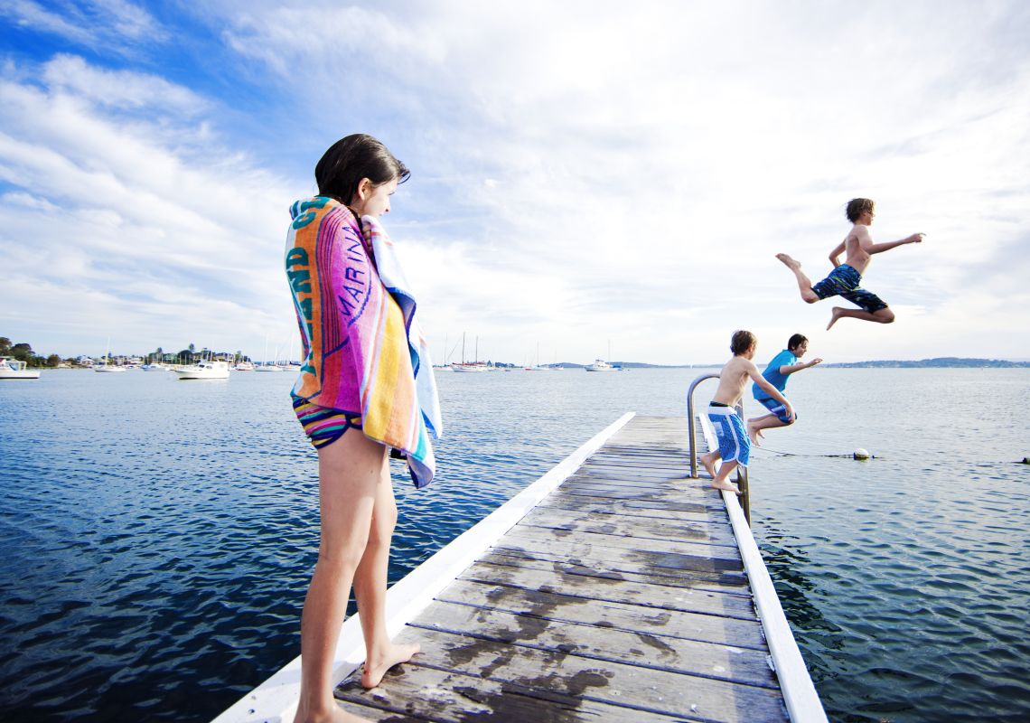 Kids jumping off the Belmont Jetty at Lake Macquarie, North Coast