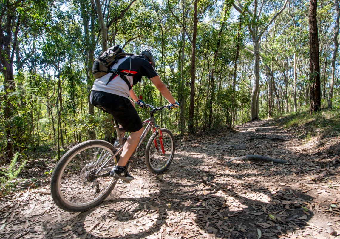 A mountain bike rider enjoying the Bombala track. It is set amongst a tranquil forest setting within Glenrock State Conservation Area, and is made up of spotted gum, ironbark and white mahogany forest.
