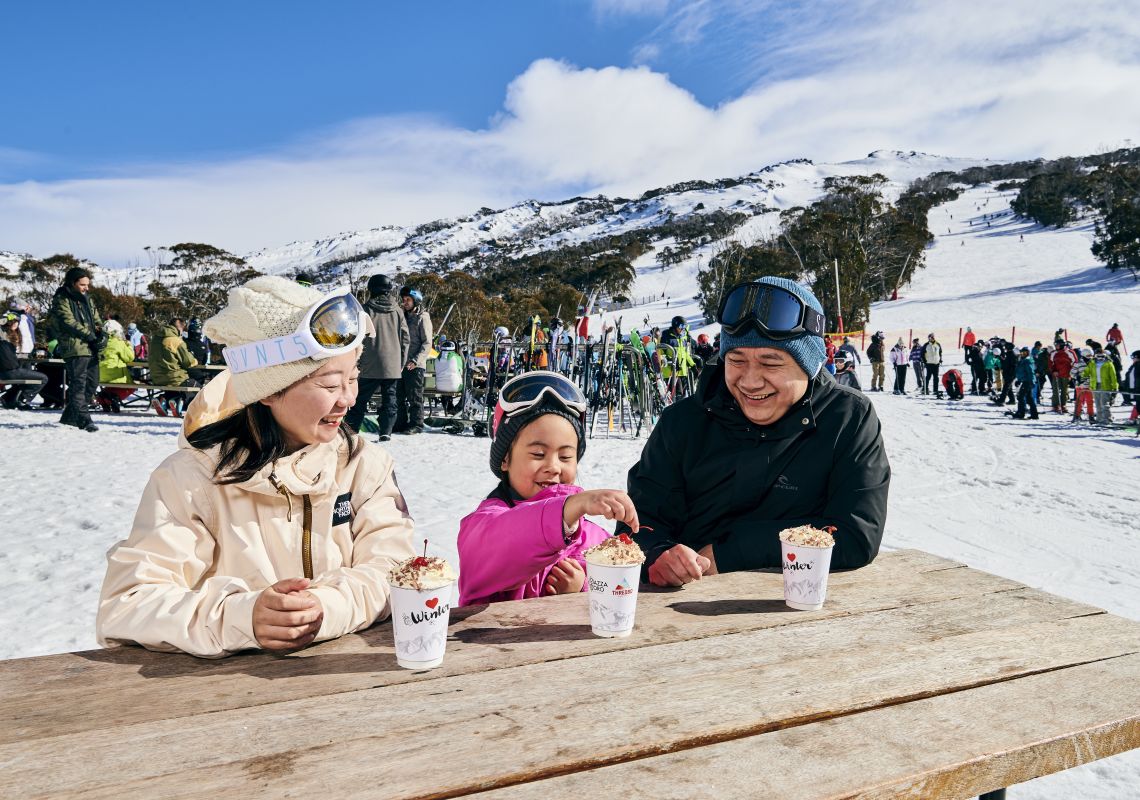 Family warming up with a hot chocolate at Thredbo ski resort in the Snowy Mountains