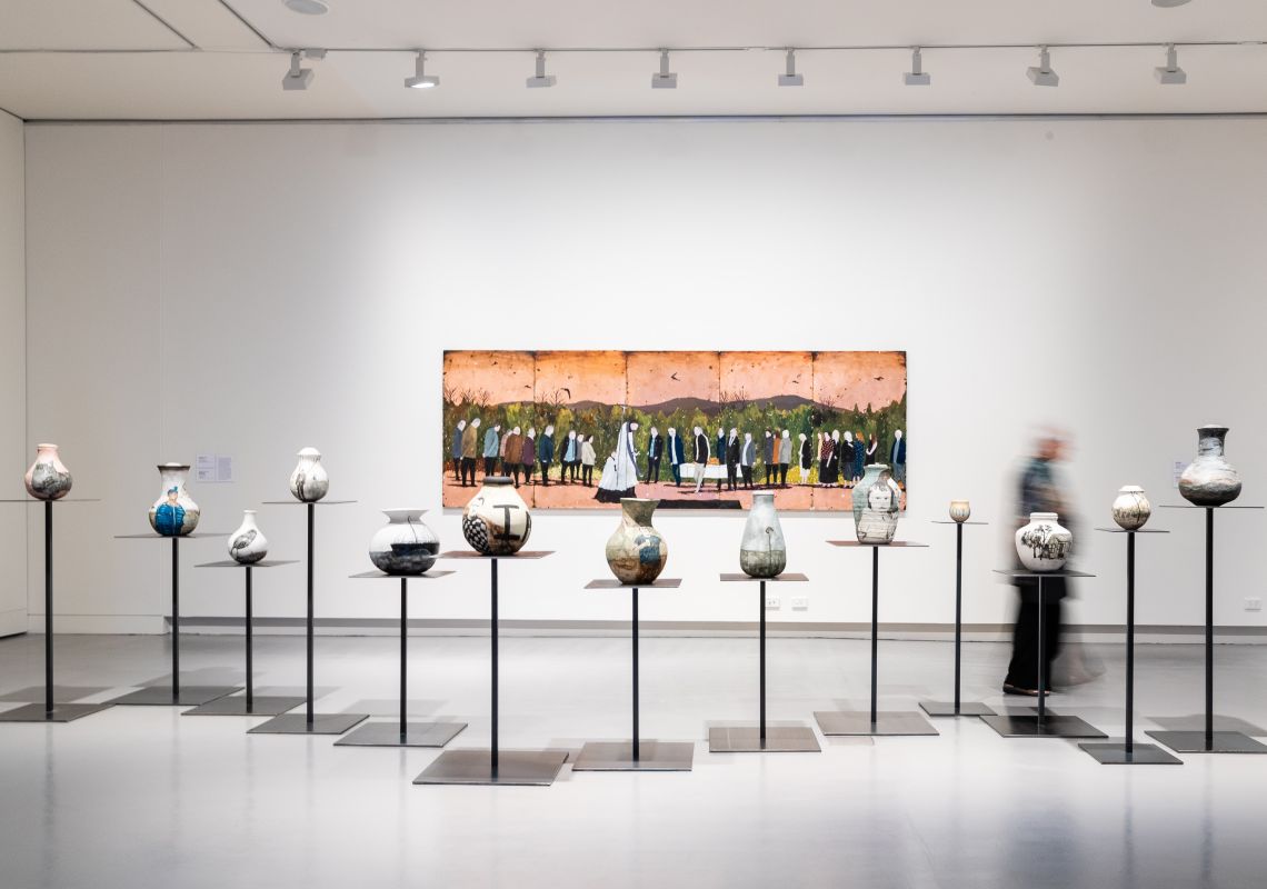 Installation view - 13 urns by Richard Lewer and Felicity Law, Richard Lewer's paining in background at Museum of Art and Culture Lake Macquarie, North Coast
