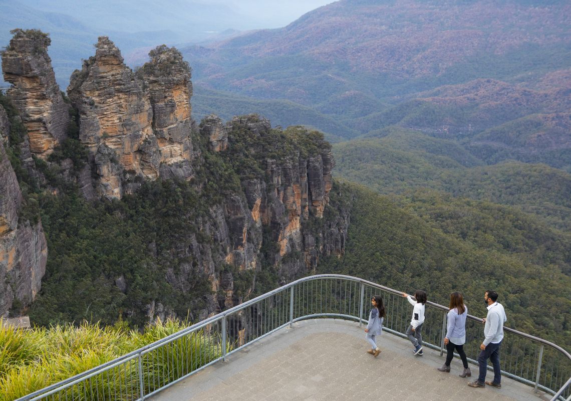 Family enjoying views across Blue Mountains National Park to the Three Sisters and Mount Solitary from Echo Point Lookout in Katoomba