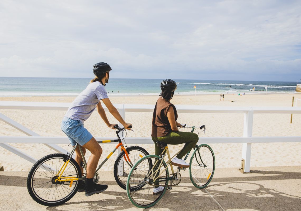 Friends cycling along Macquarie Pier at Nobbys Beach in Newcastle, North Coast