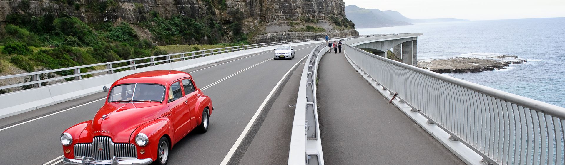 Red vintage car on Sea Cliff Bridge, between Coalcliff and Clifton