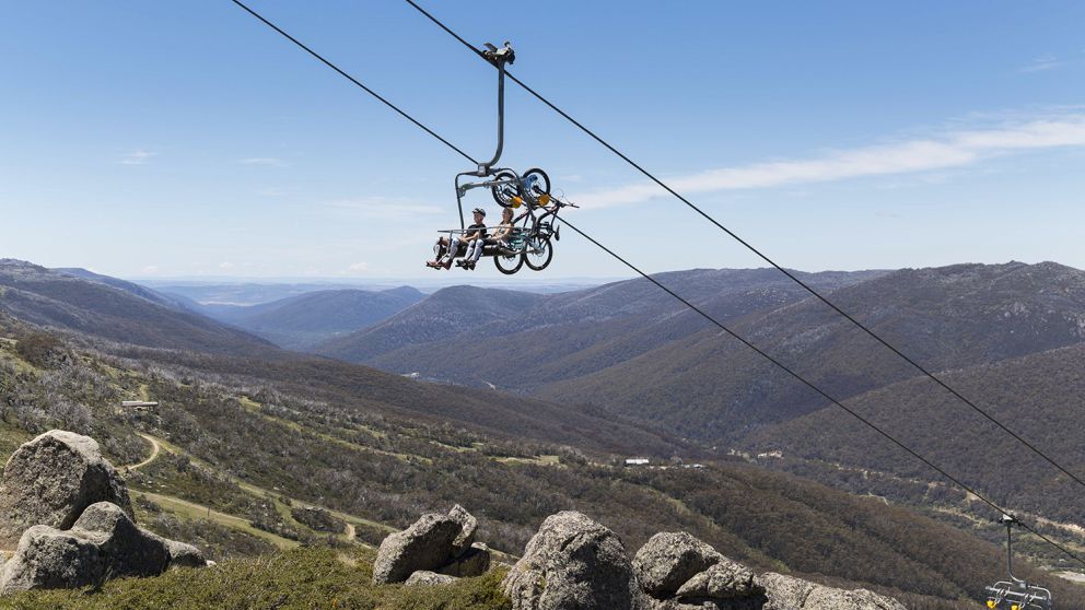 Mountain bikers taking a chairlift to the top of the Thredbo Valley Track with scenic views over Kosciuszko National Park