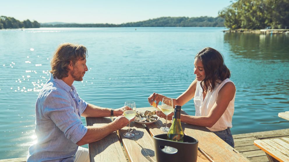 A couple having some Oysters and enjoying of drinking at Tuross Boatshed and Cafet in Tuross Head , Eurobodalla, South Coast