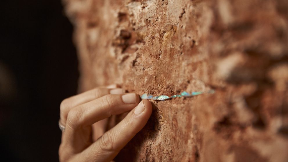 Woman inspecting a layer of opal in Red Earth Opal mine in White Cliffs