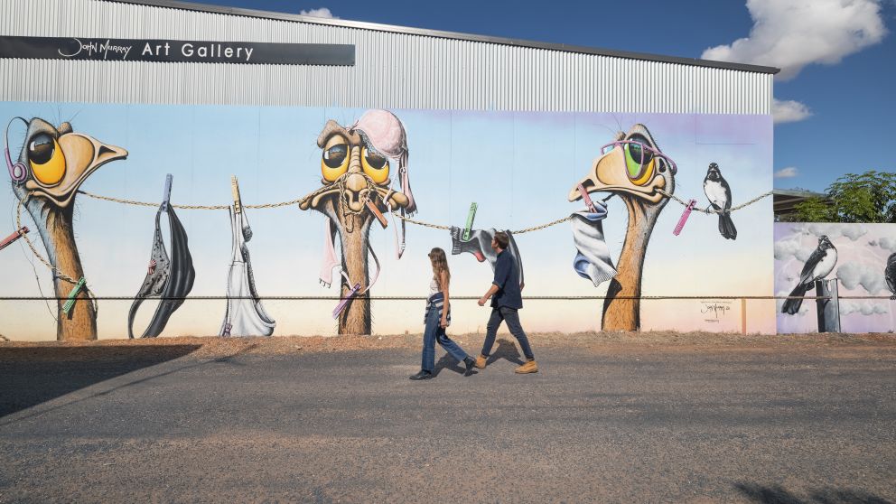 Couple viewing the mural painted on the side of the John Murray Art Gallery in Lightning Ridge, Outback NSW
