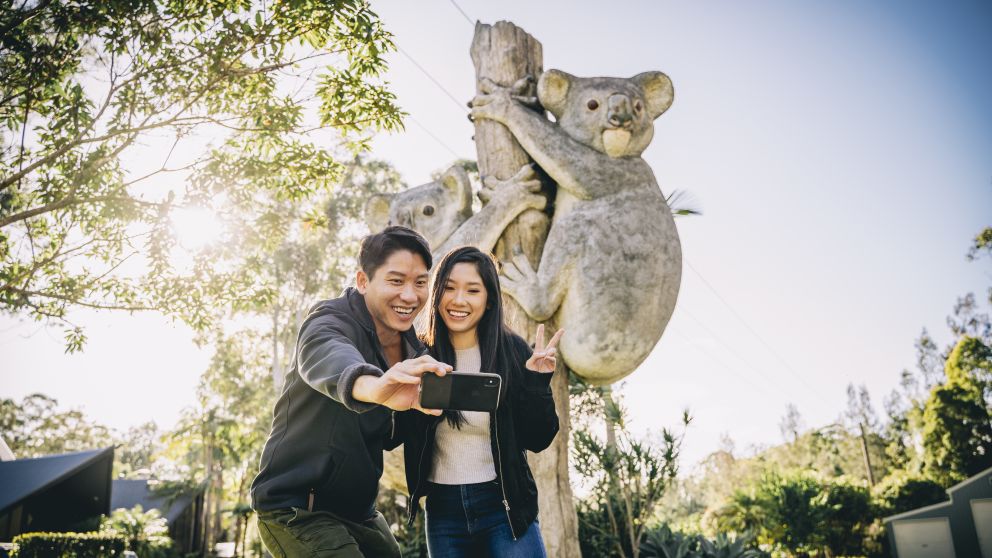 Couple taking a selfie in front of the koala sculpture at Billabong Zoo in Port Macquarie, North Coast