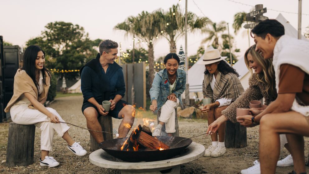 Friends roasting marshmallows and drinking hot chocolate by the pit fire at The Hideaway, Cabarita Beach