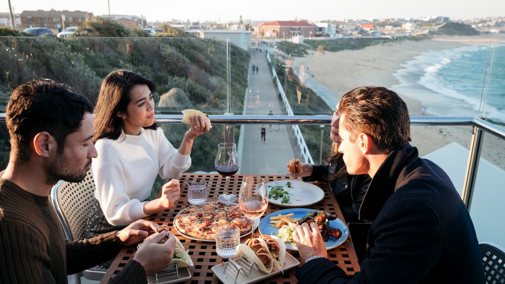 Friends enjoying food and drink with ocean views, Merewether Surfhouse, Newcastle