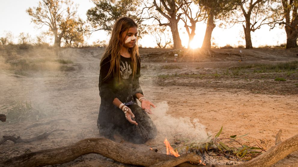 Young girl from the Barkindji nation preparing leaves for a smoking ceremony, Wilcannia