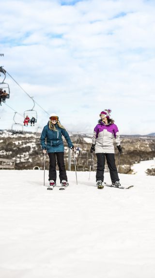 Friends skiing near ski lifts at Selwyn Snowfields in the Snowy Mountains