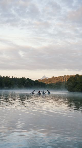 Friends enjoying an early morning kayak tour on Tweed River with scenic views of Mount Warning