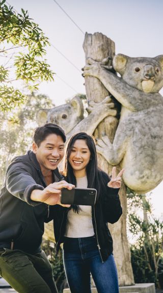Couple taking a selfie in front of the koala sculpture at Billabong Zoo in Port Macquarie, North Coast