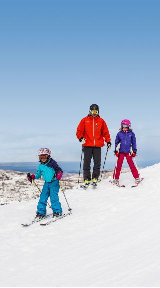 Father with daughters skiing at Perisher Ski Village in the Snowy Mountains