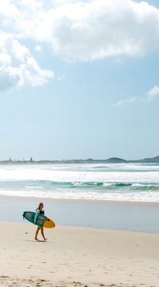 Surfer walking along Broken Head Beach, Byron Bay