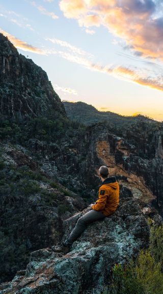 Hiker watching sunset over volcanic rock formations, Warrumbungle National Park