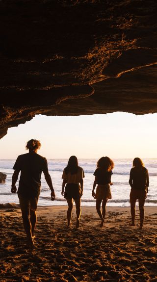  Four friends enjoying a warm sunrise inside cave, Caves Beach, Lake Macquarie