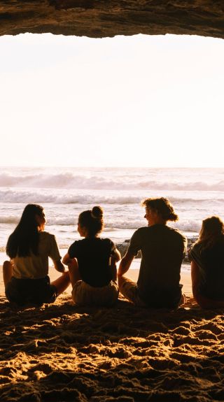  Four friends enjoying a warm sunrise inside cave, Caves Beach, Lake Macquarie