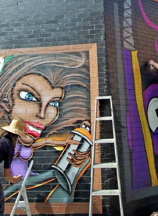 Street artists spray paint walls in The Back Alley Gallery, Lismore