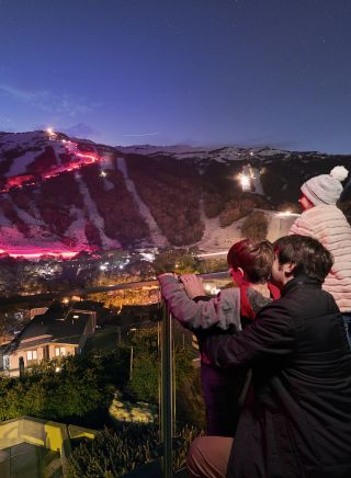 Family watching skiiers and snowboarders participating in the Saturday night flare run tradition at Thredbo in the Snowy Mountains