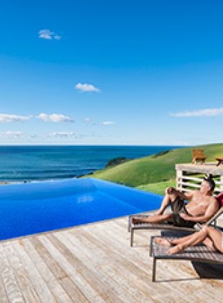Couple relaxing by the pool at Ocean Farm luxury accommodation in Gerringong. 