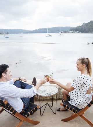 Couple enjoying evening drinks with a view at The Box on the water restaurant and bar at Ettalong beach in Woy Woy, Central Coast 
