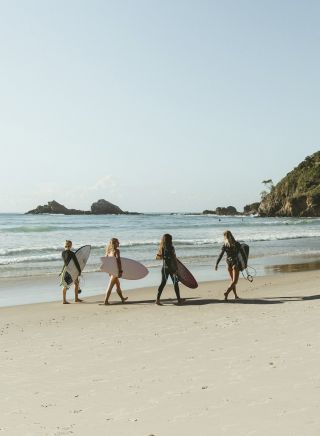 Surfers walking along Broken Head Beach in Byron Bay, North Coast